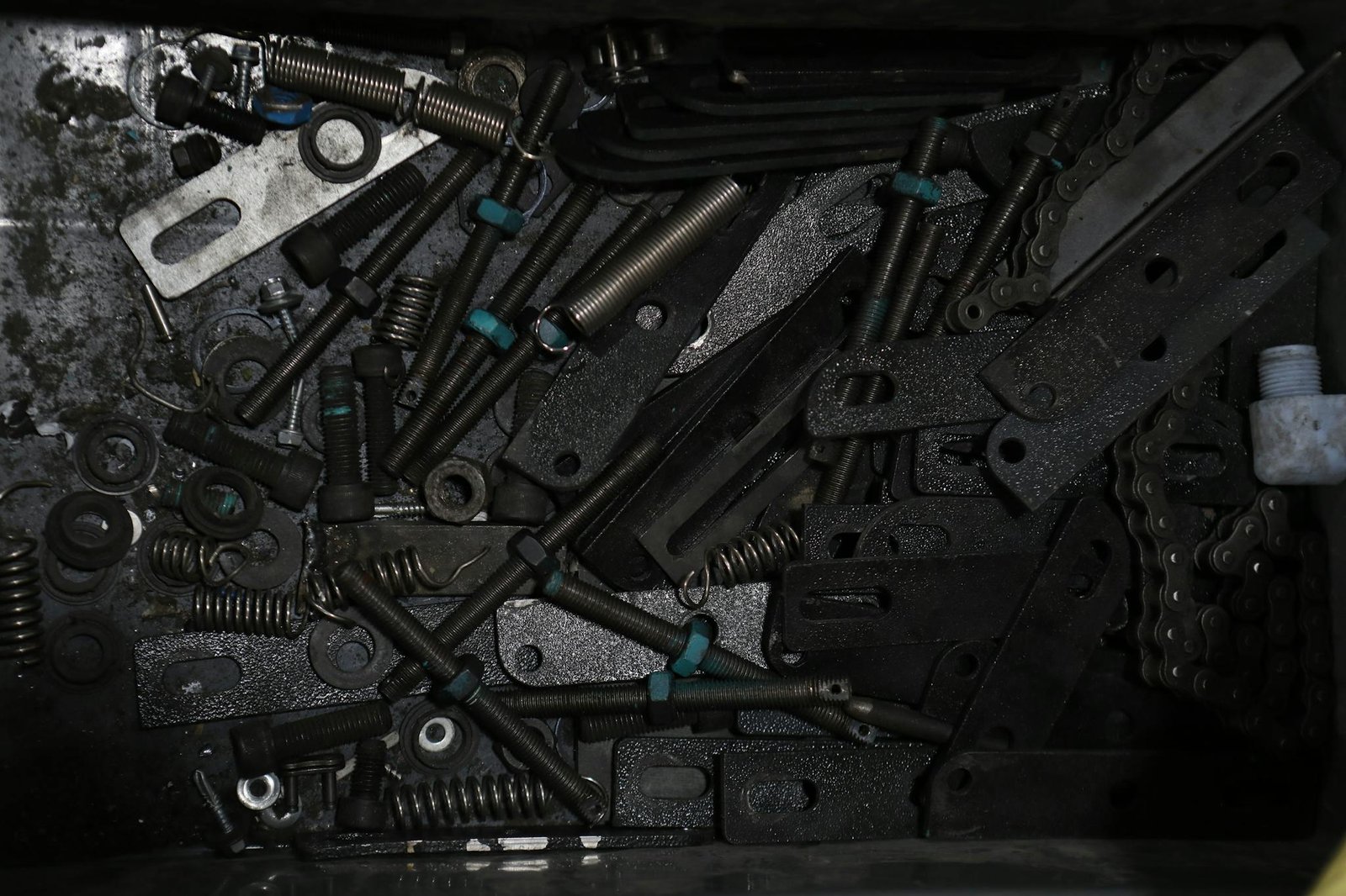 high angle view of assorted metal fasteners springs and chains in a box. 6972571